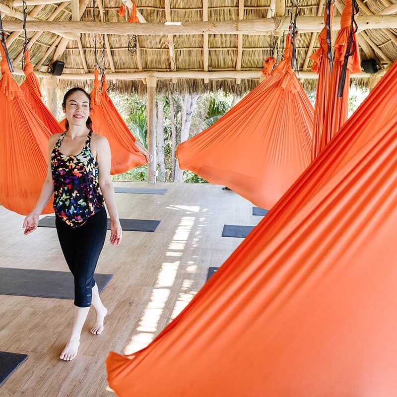 Sophia Mallie, an aerial yoga instructor, walks among her students floating in their aerial yoga hammocks in Xinalani.