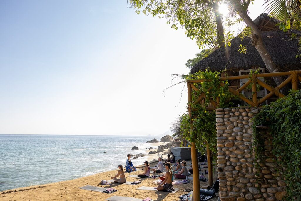 Yoga students sit in Xinalani's Sand Terrace, right next to the ocean.