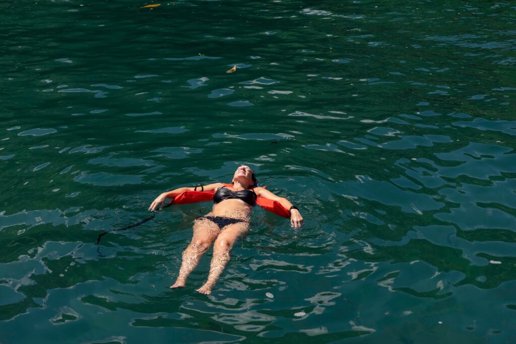 Person floating in calm ocean water, releasing physical tension