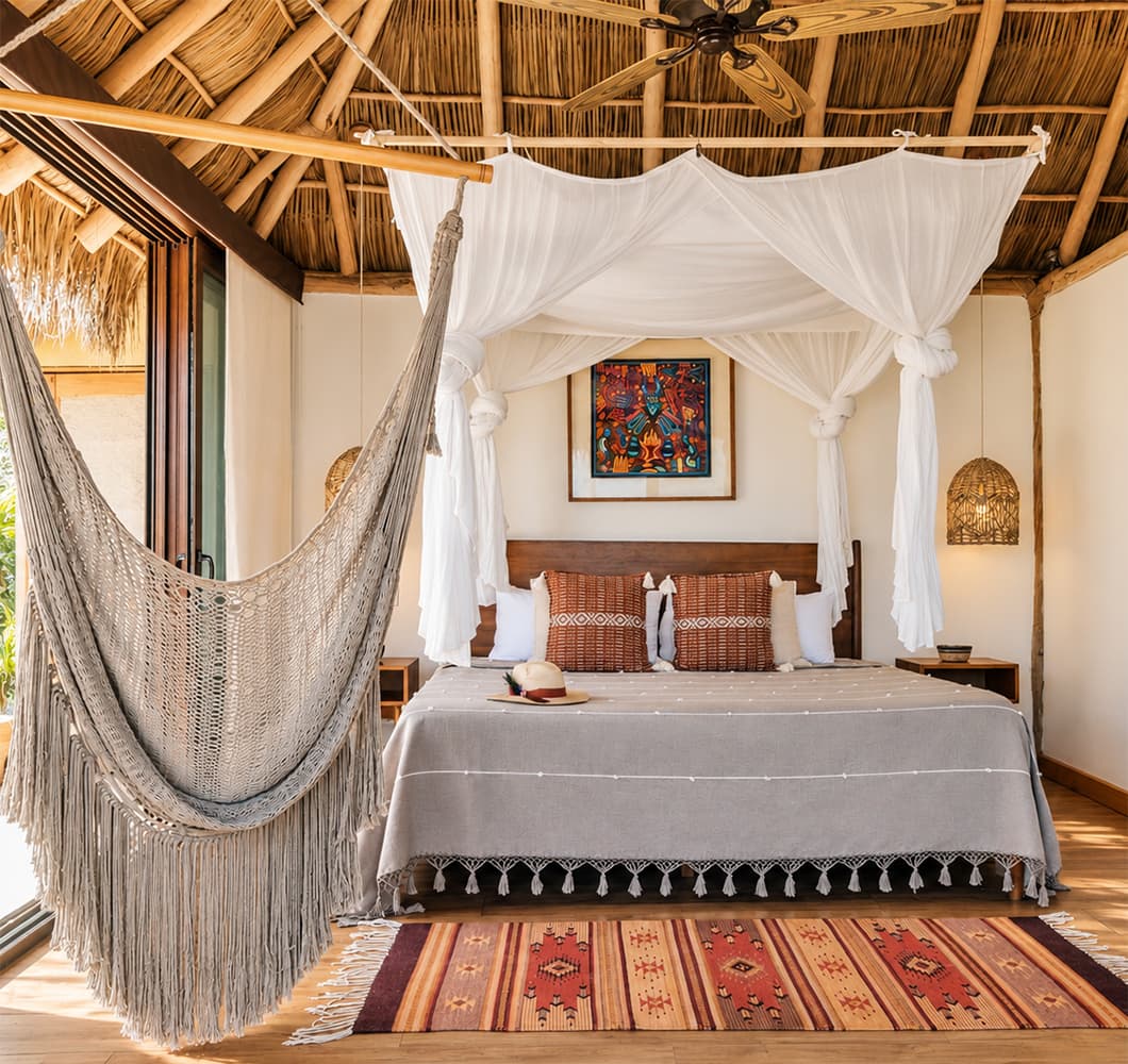 Room interior with canopy bed and hammock at Xinalani