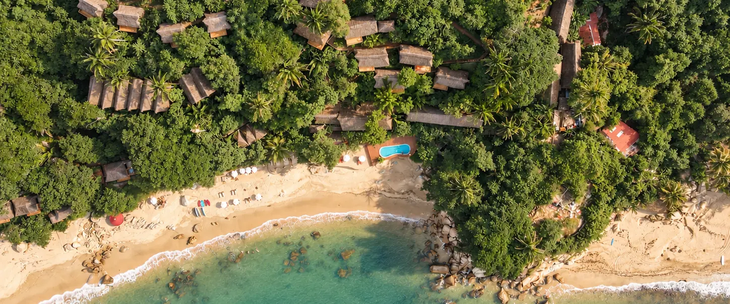 Vista aérea de la playa, la alberca y las casitas en la selva de Xinalani